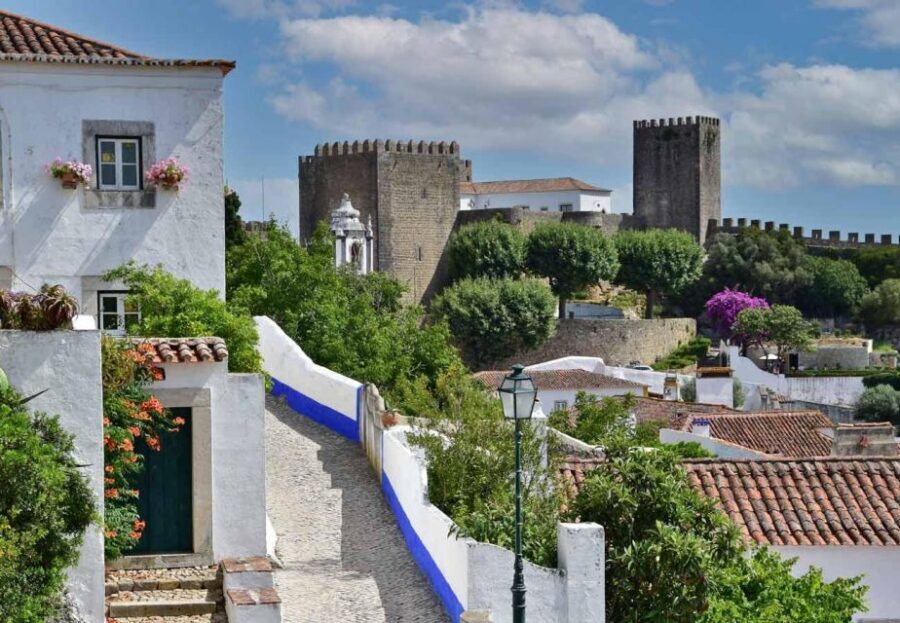 From Lisbon: Shared Tour to Fátima, Óbidos, Batalha e Nazaré - Óbidos: cobblestones, walls, and a hilltop castle panorama